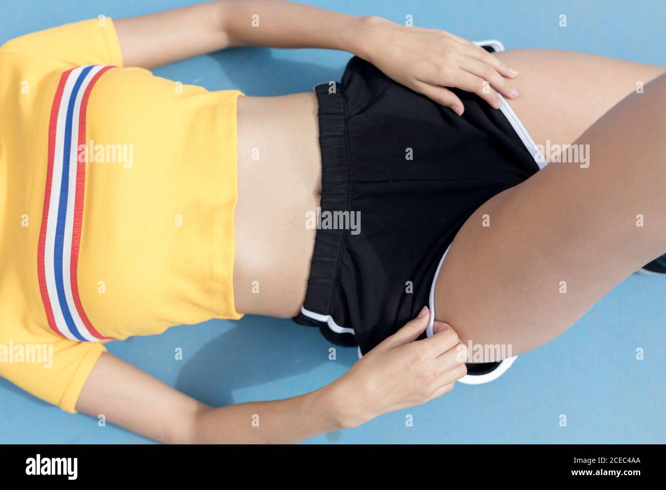 Crop sottile femmina in abiti sportivi che si stagliano su sfondo blu Foto Stock