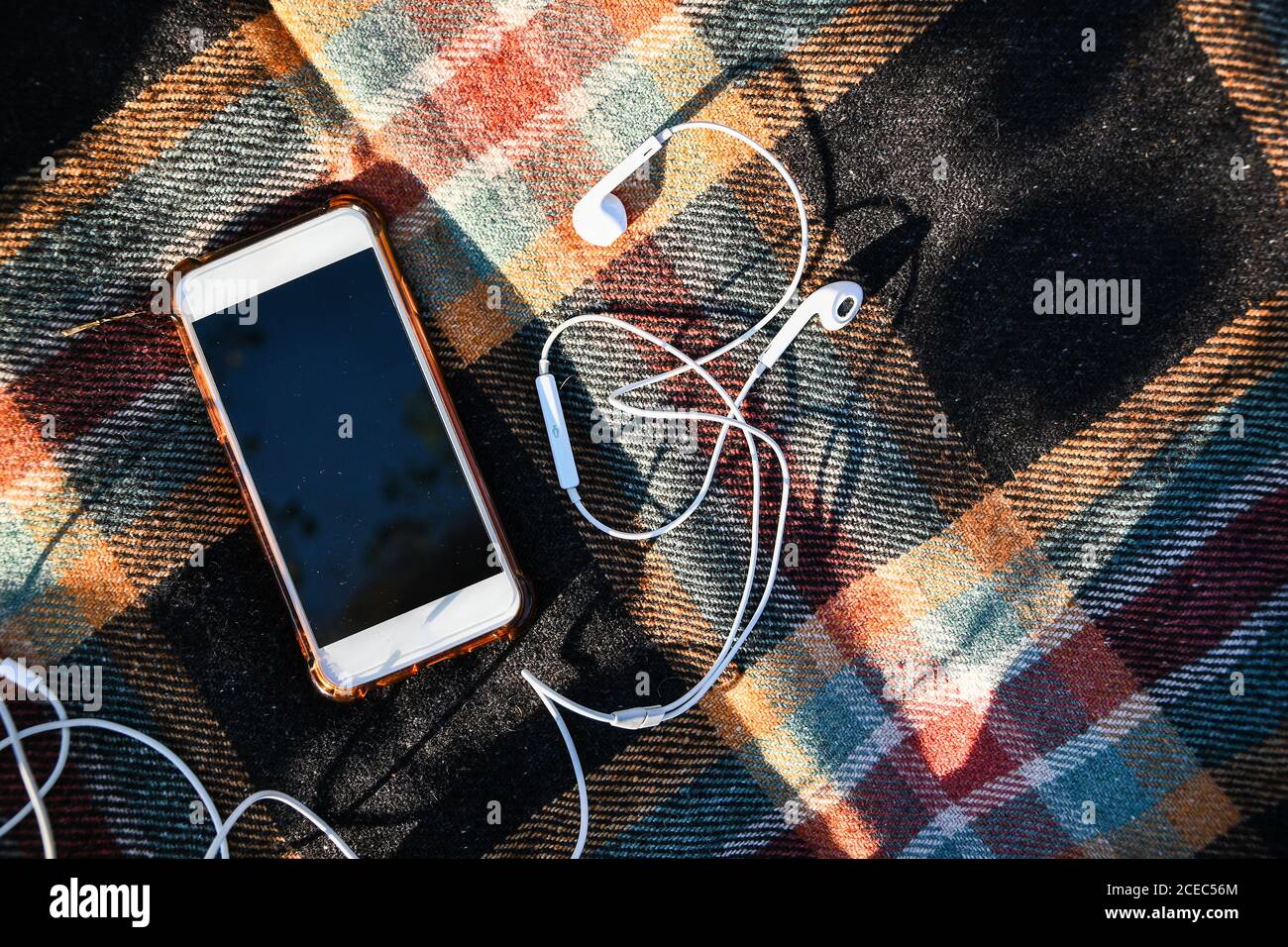 Smartphone con cuffie sui comodi pullover. Vista dall'alto. Piatto autunnale. Podcast per l'ascolto all'aperto. Foto Stock