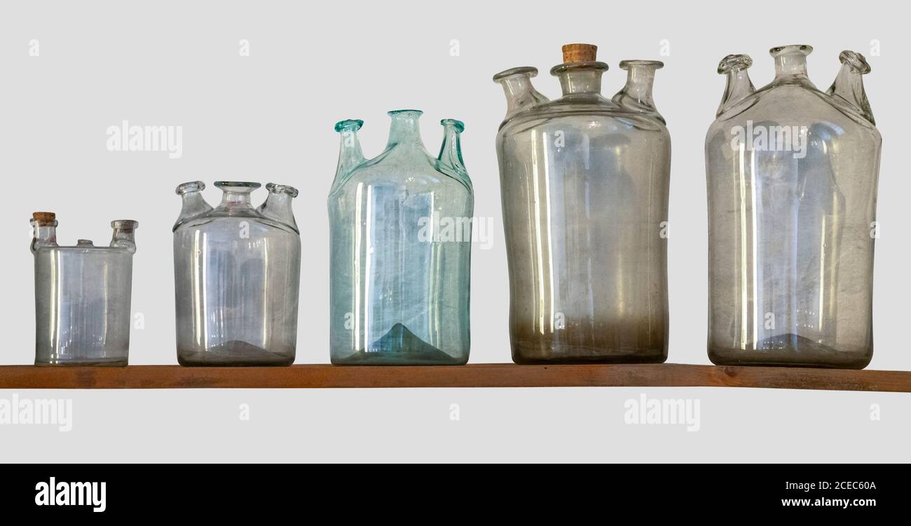 un sacco di bottiglie di vetro storico su un ripiano in grigio indietro Foto Stock
