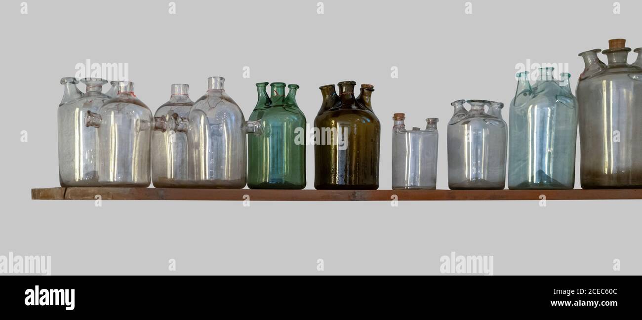 un sacco di bottiglie di vetro storico su un ripiano in grigio indietro Foto Stock