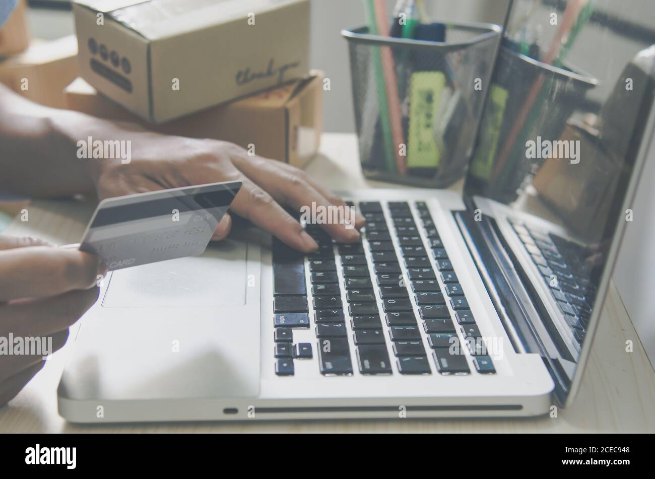 Mano dell'uomo che tiene lo shopping in linea della carta di credito con il calcolatore. Concetto di business online. Tonalità vintage. Foto Stock