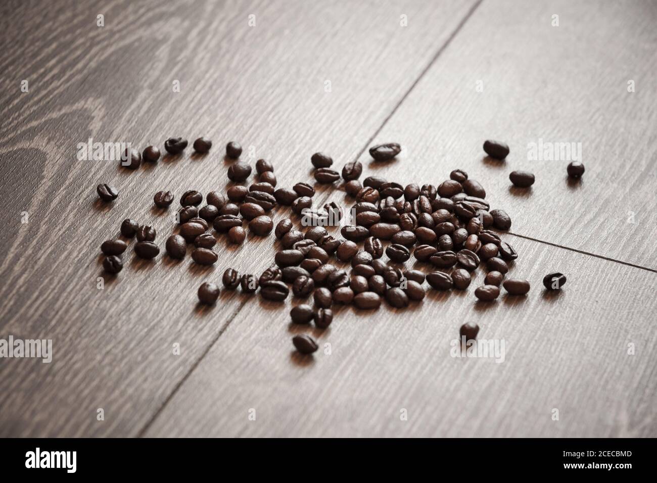 I chicchi di caffè torrefatti scuri si trovano sulla scrivania in legno grigio, foto con messa a fuoco morbida selettiva Foto Stock