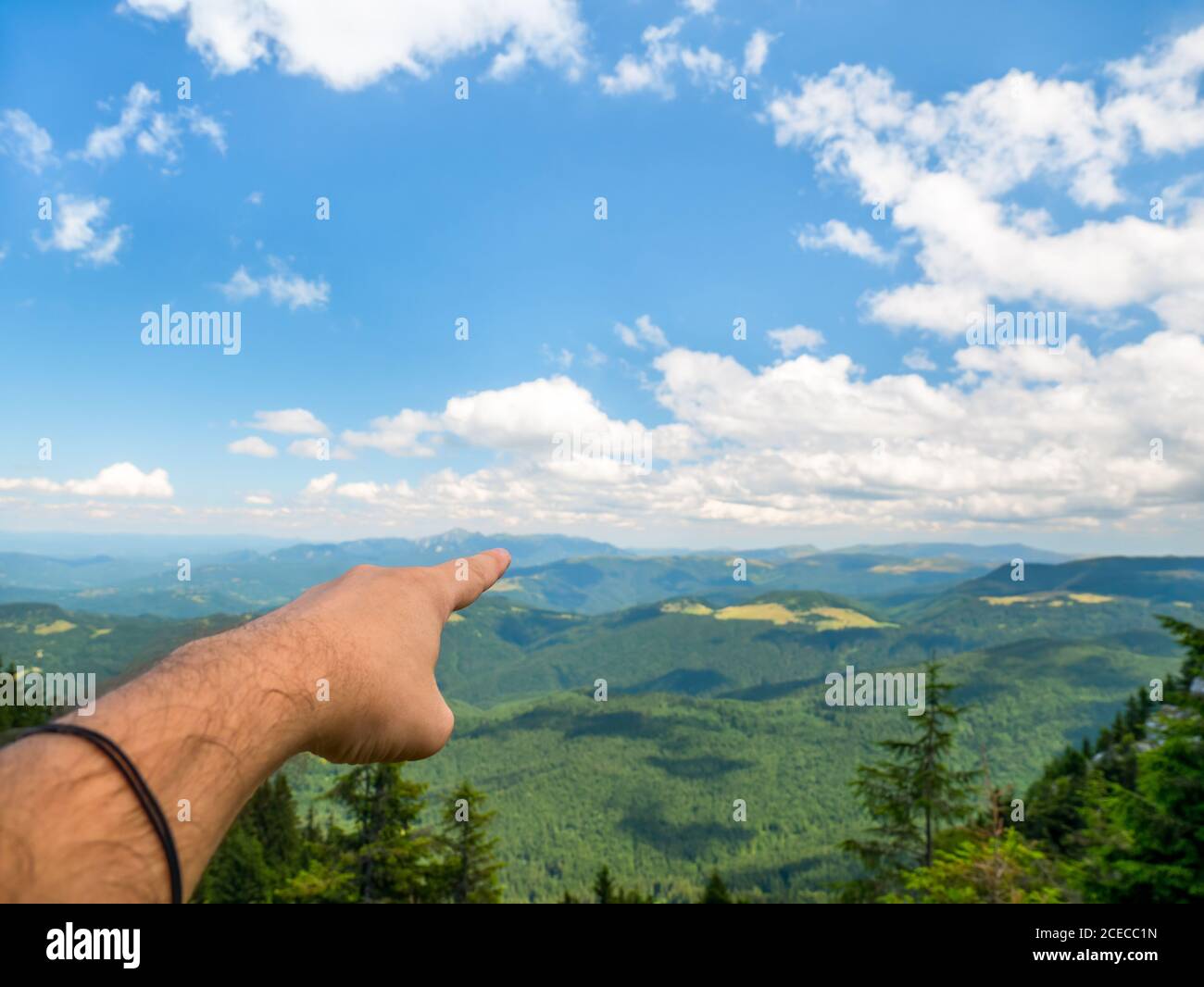 La mano dell'uomo che punta verso le tane e il cielo blu. Splendido paesaggio dalle montagne di Piatra Mare (BG Rock), parte delle montagne dei Carpazi Foto Stock