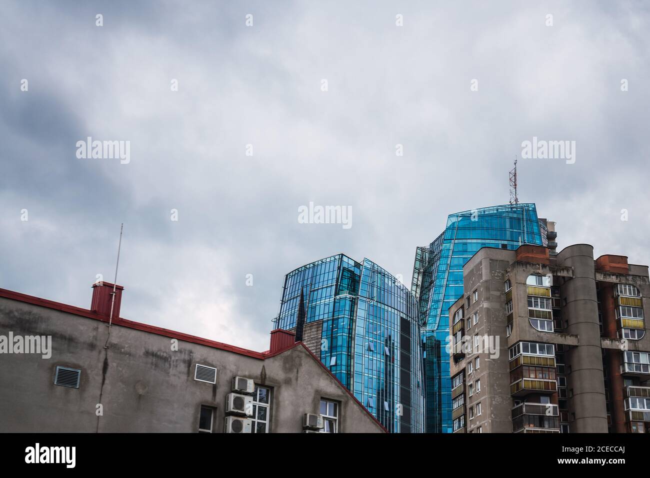 Da sotto colpo di spesse nubi che scorrono sul cielo sopra alti edifici antichi e moderni in città Foto Stock
