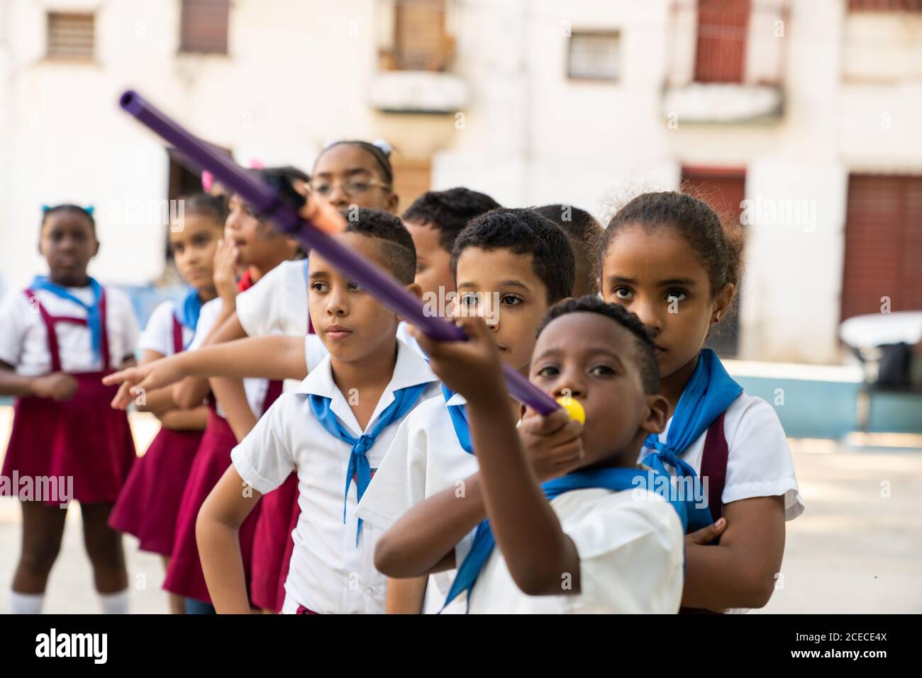 LA HABANA, CUBA - NOVEMBRE, 6, 2018: Ragazzo afroamericano che tiene il puntatore vicino alla bocca e alla coda dei bambini in attesa in uniformi dei pionieri a Cuba Foto Stock