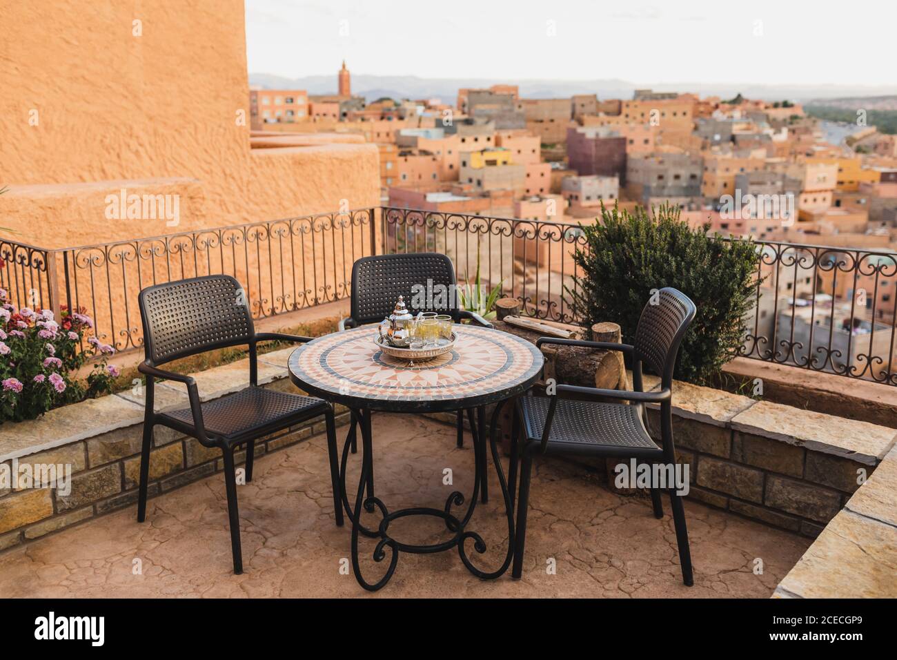 Tavolo rotondo a mosaico sulla terrazza con tradizionale tè marocchino alla menta. Splendida vista della città vecchia di Boumalne in Marocco al tramonto. Foto Stock