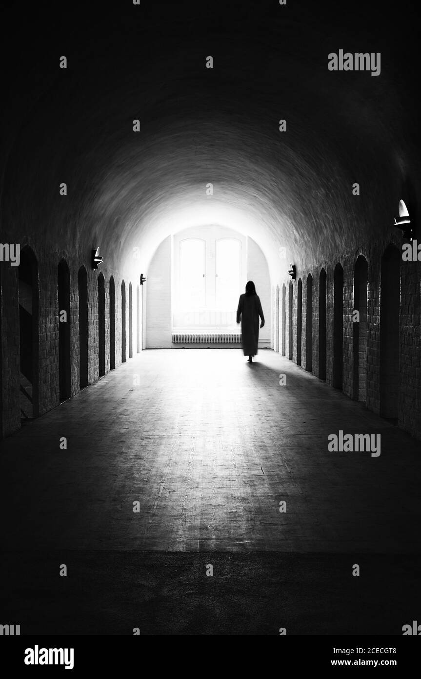 Silhouette di donna sleepwalking irriconoscibile in ospedale mentale medievale Foto Stock