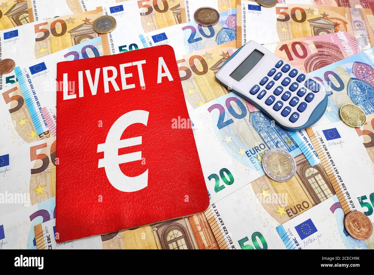 Livret A e una calcolatrice sulla parte superiore di una pila di banconote e monete in euro. Il Livret A è un prodotto finanziario storico offerto dalle banche francesi. Foto Stock