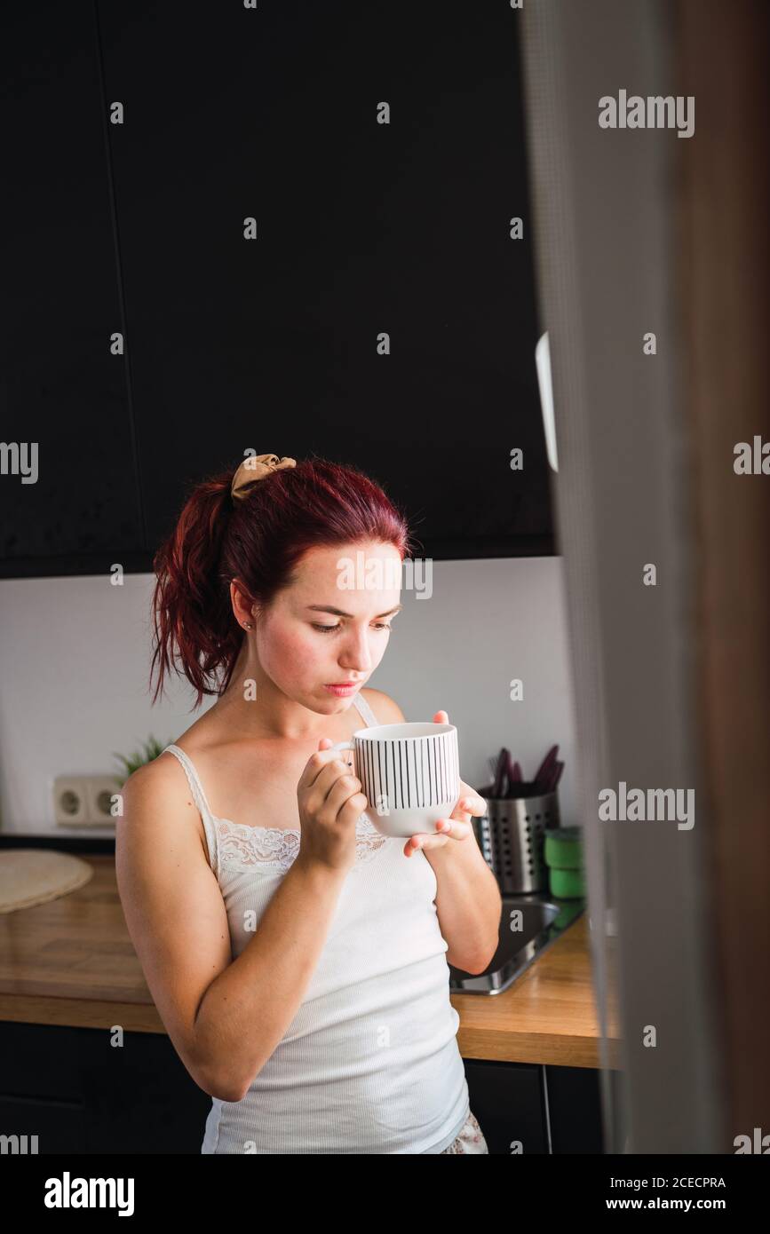 Donna di bere il caffè in cucina Foto Stock