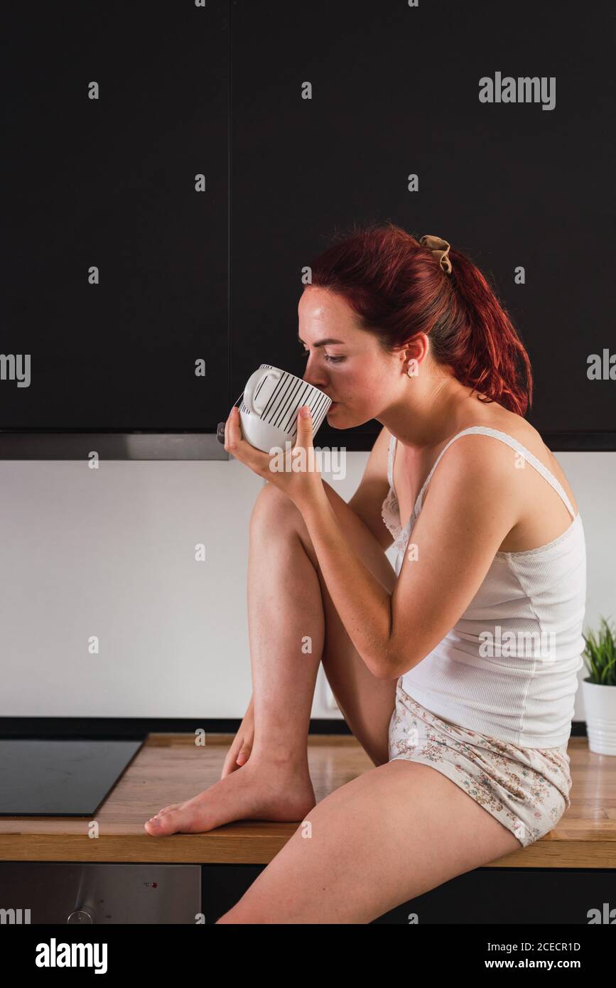 Donna di bere il caffè in cucina Foto Stock