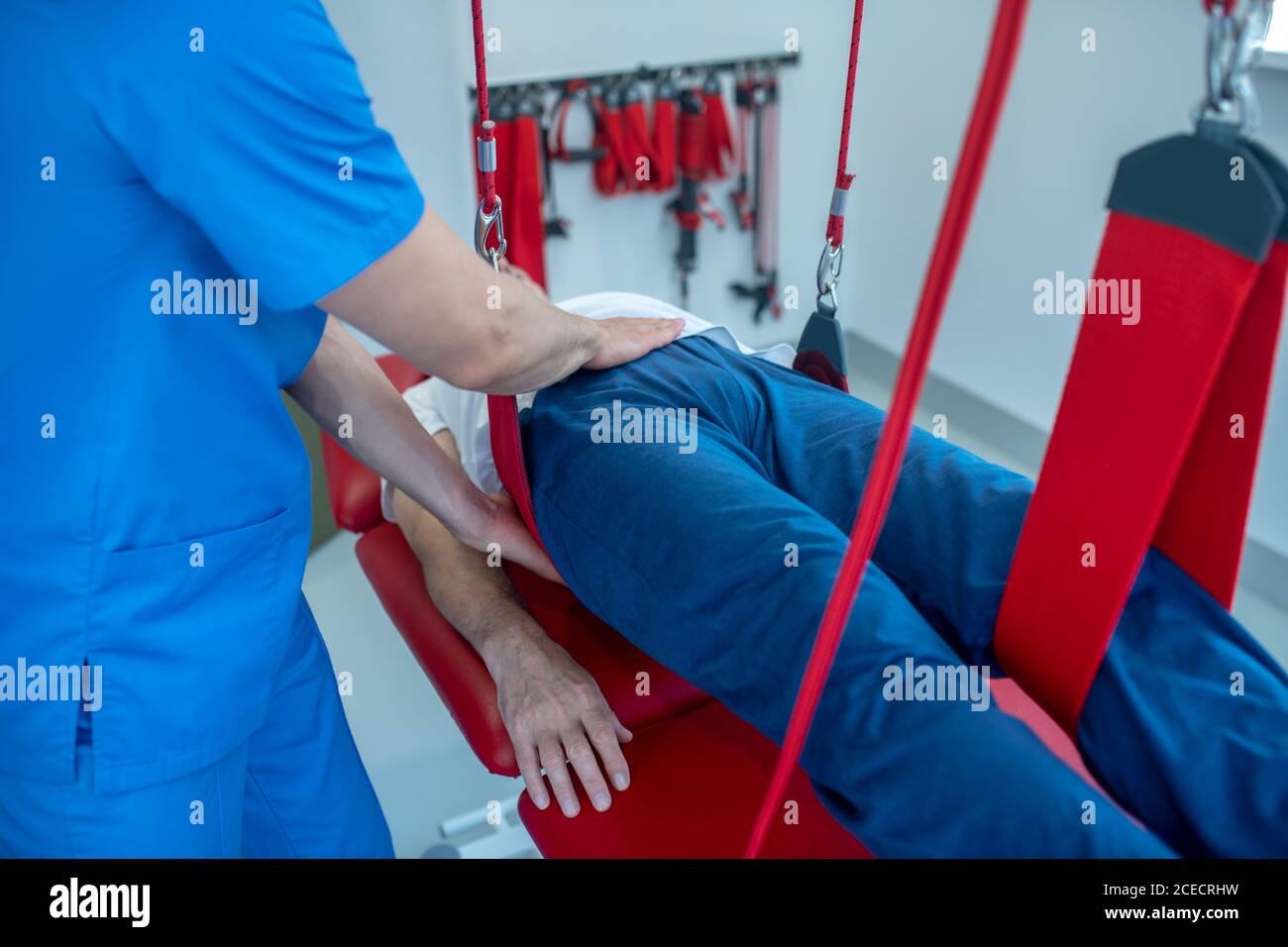 Mani di medico riabilitatore e paziente menzogna, nessun volto Foto Stock