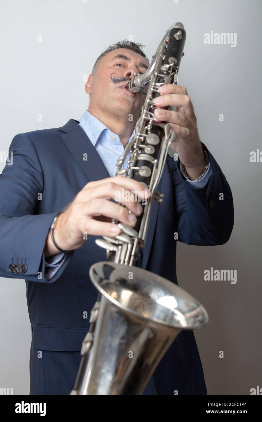 Un uomo, scuro, capelli corti, suona il clarinetto basso. Studio, sfondo chiaro. Foto di alta qualità Foto Stock