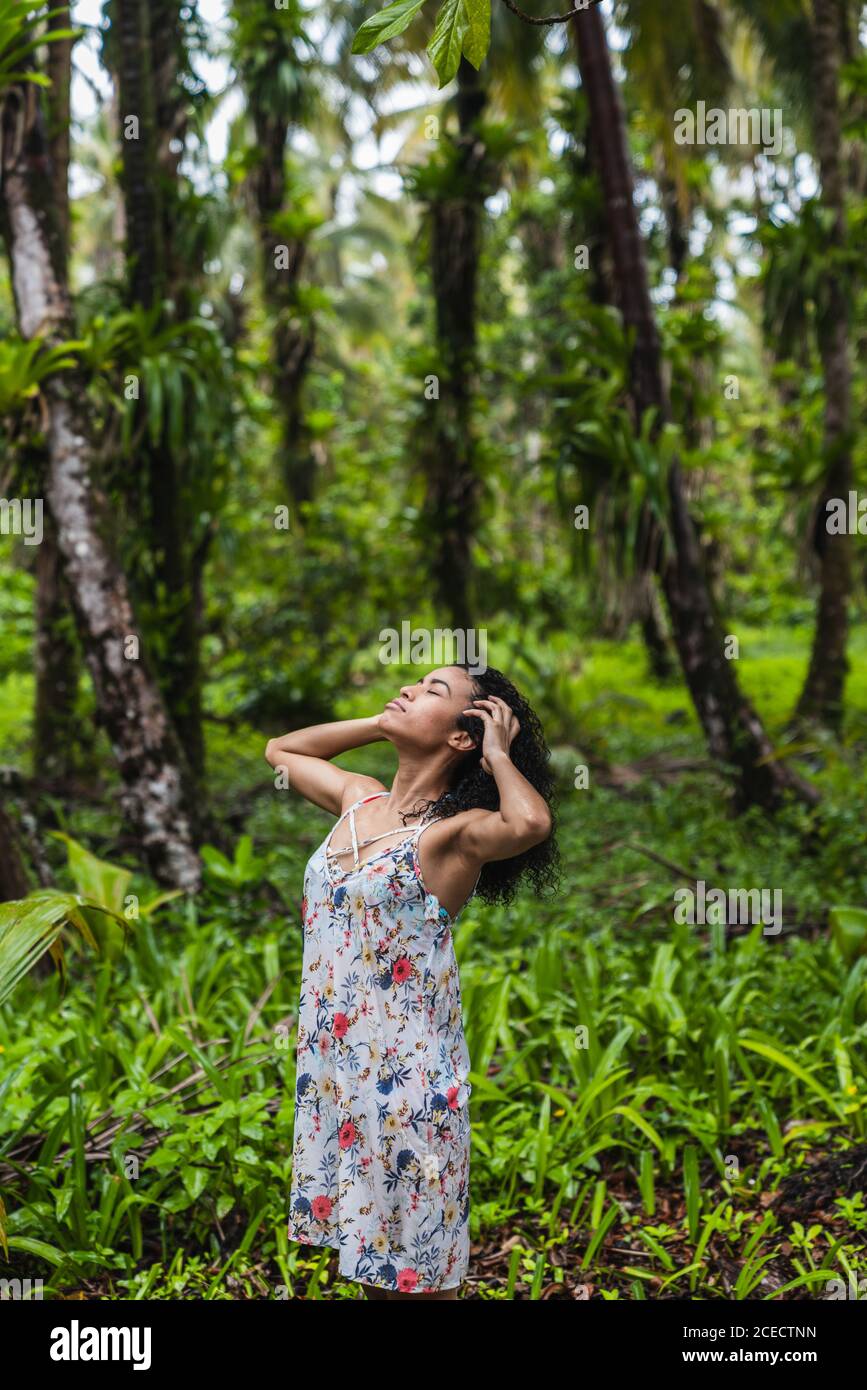 Attraente donna ispanica con testa e mani su capelli in verde foresta nelle Isole Bocas del Toro, Panama Foto Stock