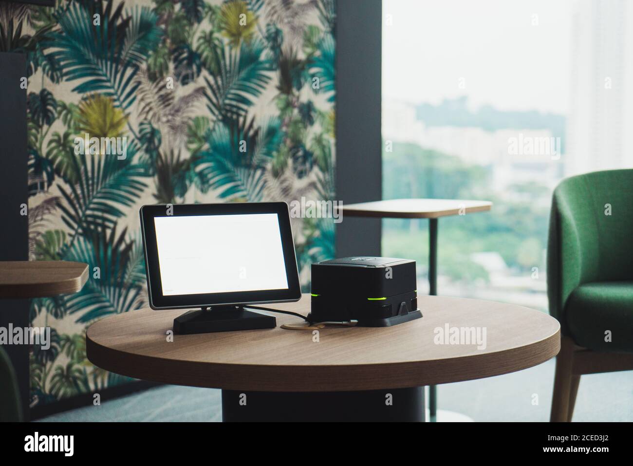 Monitor vuoto e unità di sistema di piccole dimensioni di un PC moderno in piedi Su tavolo rotondo in legno in elegante camera a Singapore Foto Stock