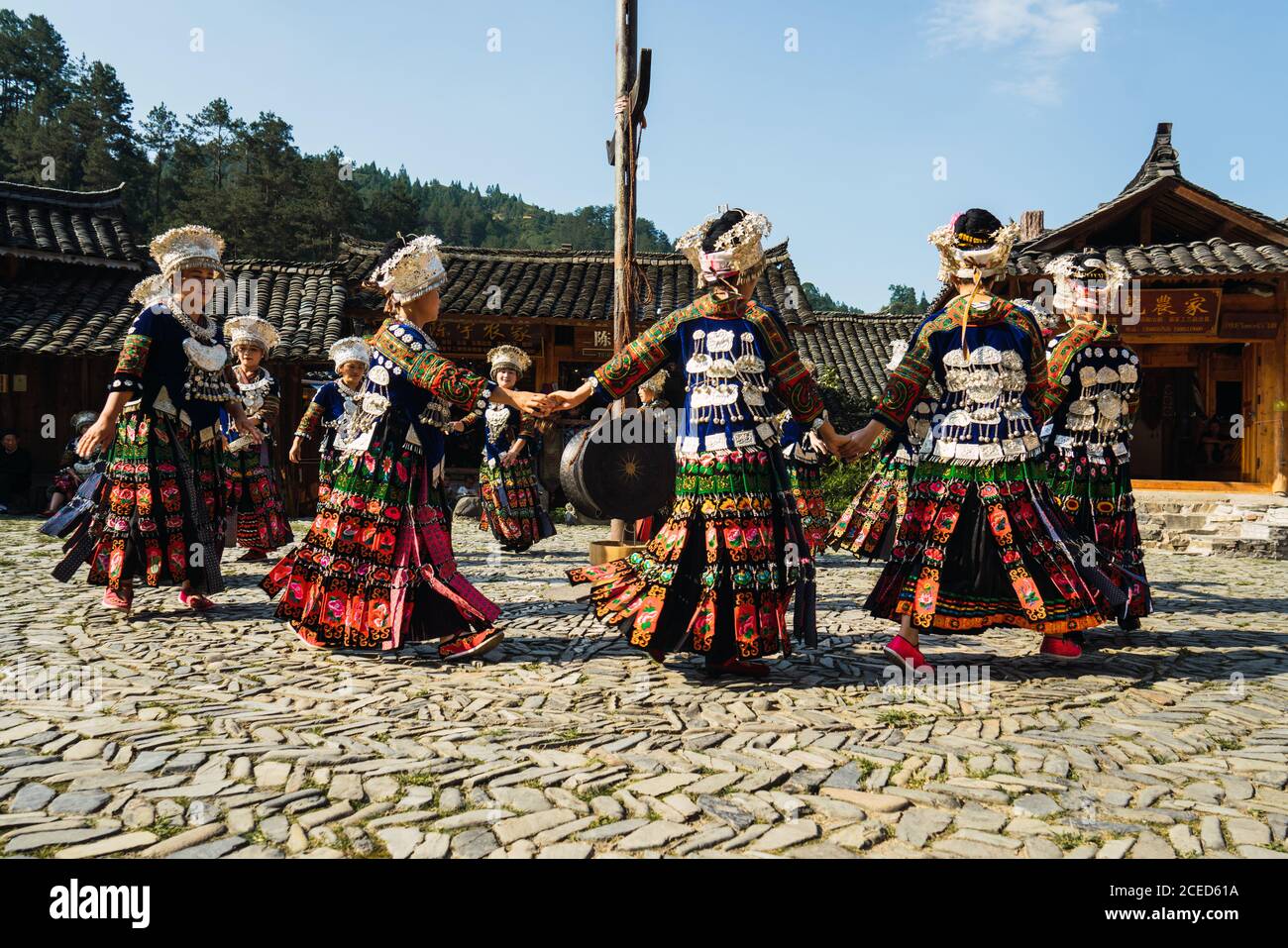 GUINZHOU, CINA - 14 GIUGNO 2018: Donne del gruppo etnico Miao in costumi luminosi con ornamenti colorati e headdresses che eseguono la danza tradizionale festival sulla piazza del villaggio nella soleggiata giornata estiva nella provincia di Guizhou in Cina Foto Stock