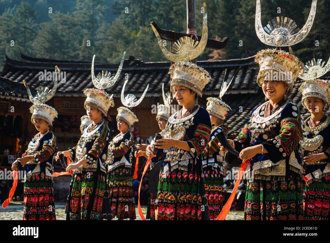 GUINZHOU, CINA - 14 GIUGNO 2018: Donne del gruppo etnico Miao in costumi luminosi con ornamenti colorati e headdresses che eseguono la danza tradizionale festival sulla piazza del villaggio nella soleggiata giornata estiva nella provincia di Guizhou in Cina Foto Stock
