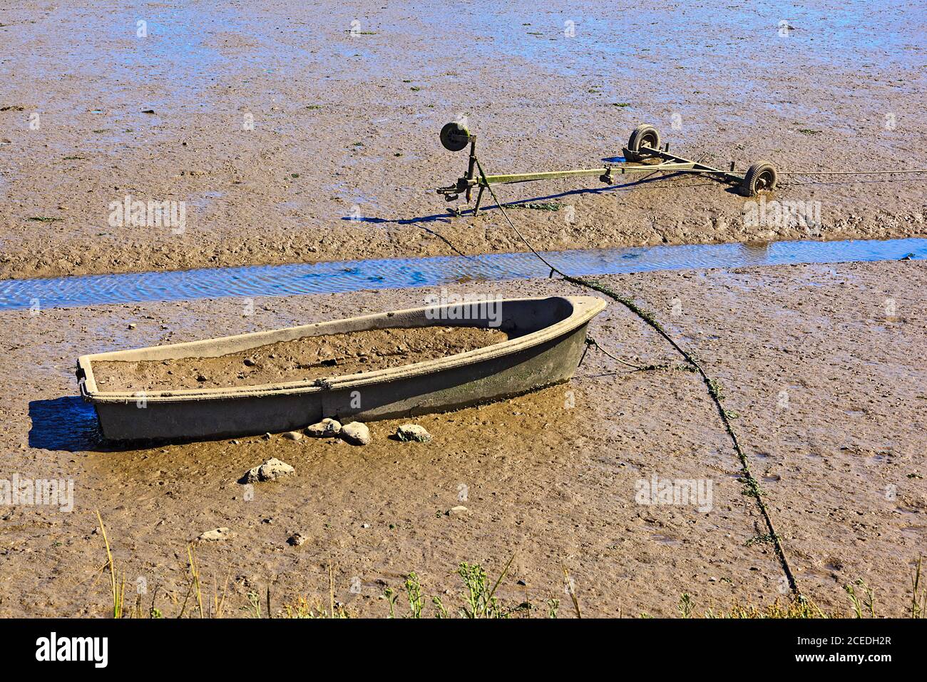 Vecchia barca e rimorchio bloccati nel fango a Brancaster Staithe, Norfolk, Regno Unito Foto Stock