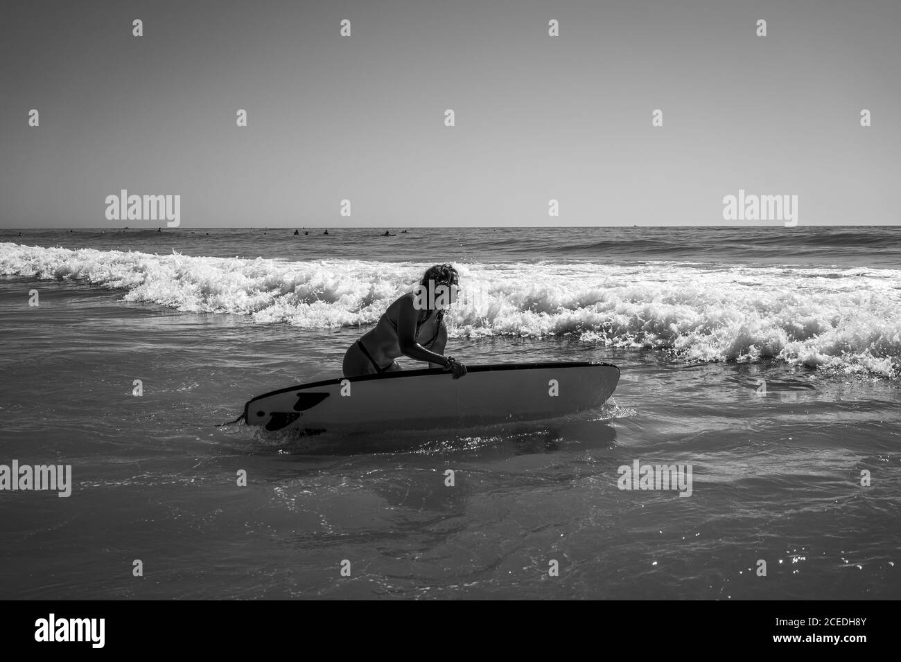 Immagine in scala di grigi di una donna caucasica che naviga in mare ondulato A Cadice Foto Stock