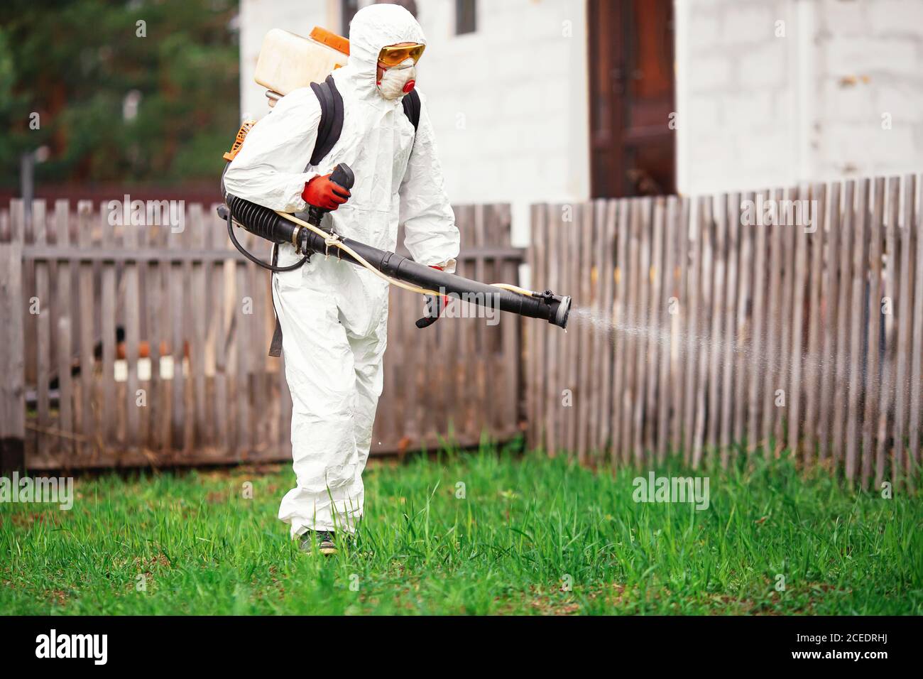 Disinfettante in tuta protettiva tratta territorio di giardino di casa  spruzza veleno da zanzare, zecche e pesti Foto stock - Alamy