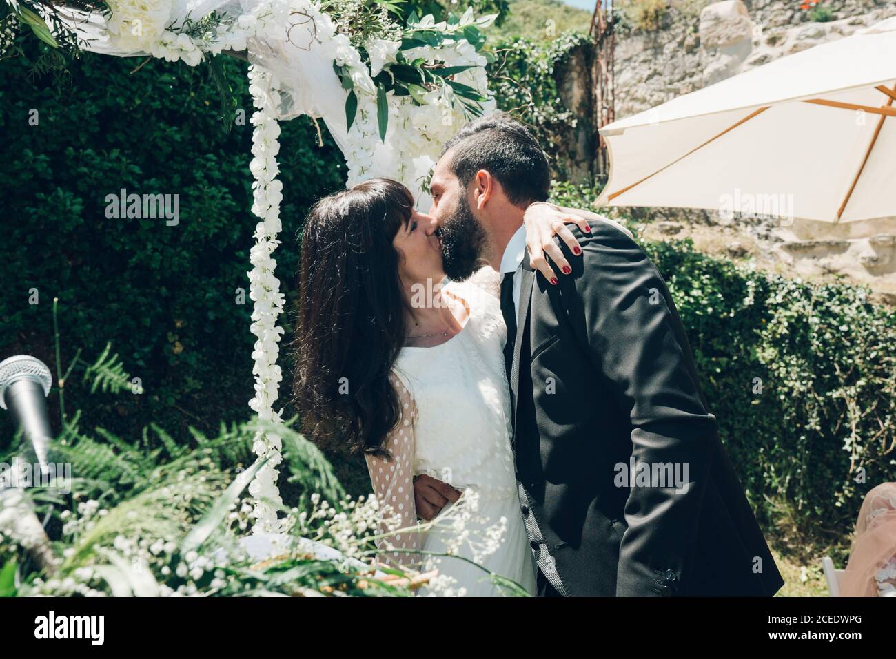 Giovane sposa e sposo che si baciano alla cerimonia nuziale Foto Stock