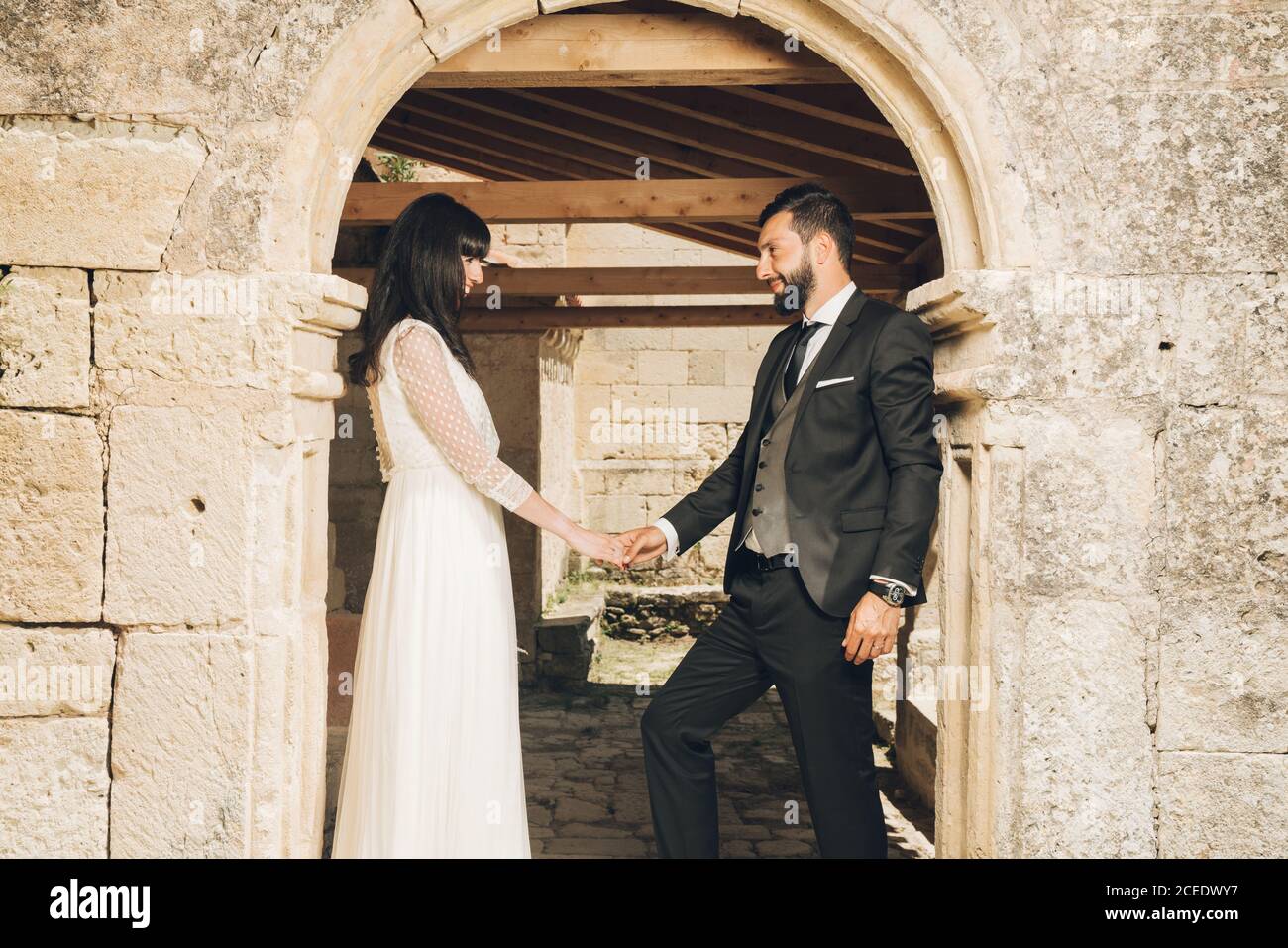 Giovane sposa e sposo in piedi insieme sotto e arco Foto Stock