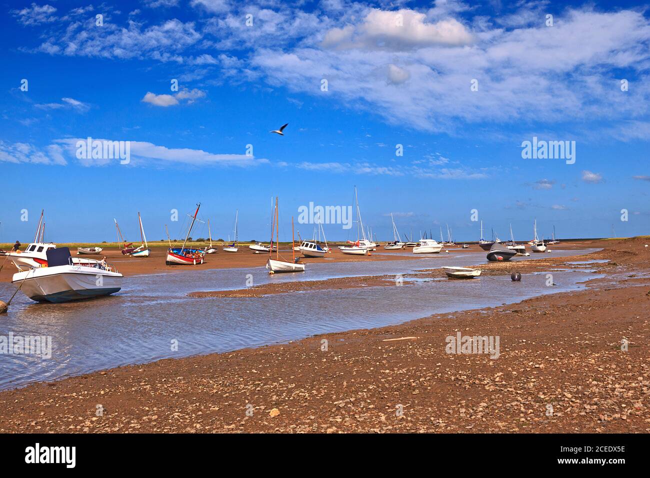 Le barche si sono arenate sul Creek a bassa marea a Brancaster Staithe, Norfolk, Regno Unito Foto Stock