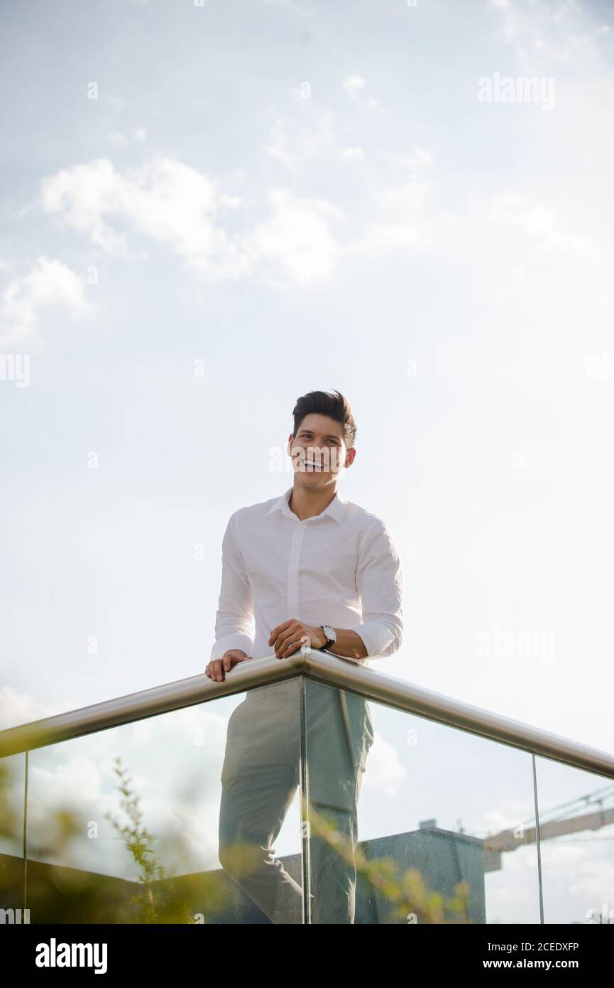 Giovane uomo appoggiato su parapetto Foto Stock