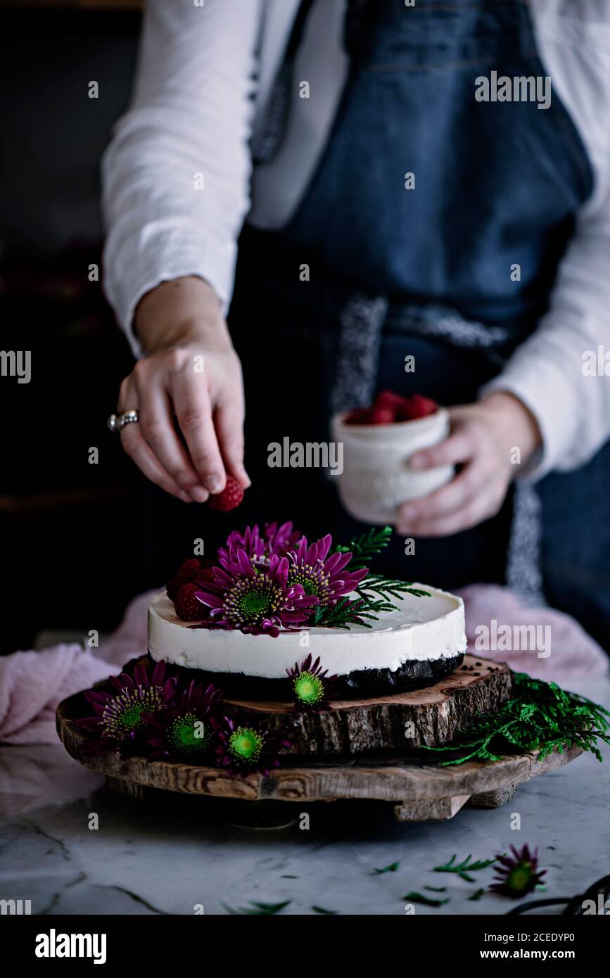 Crop Donna decorazione torta con bacche Foto Stock