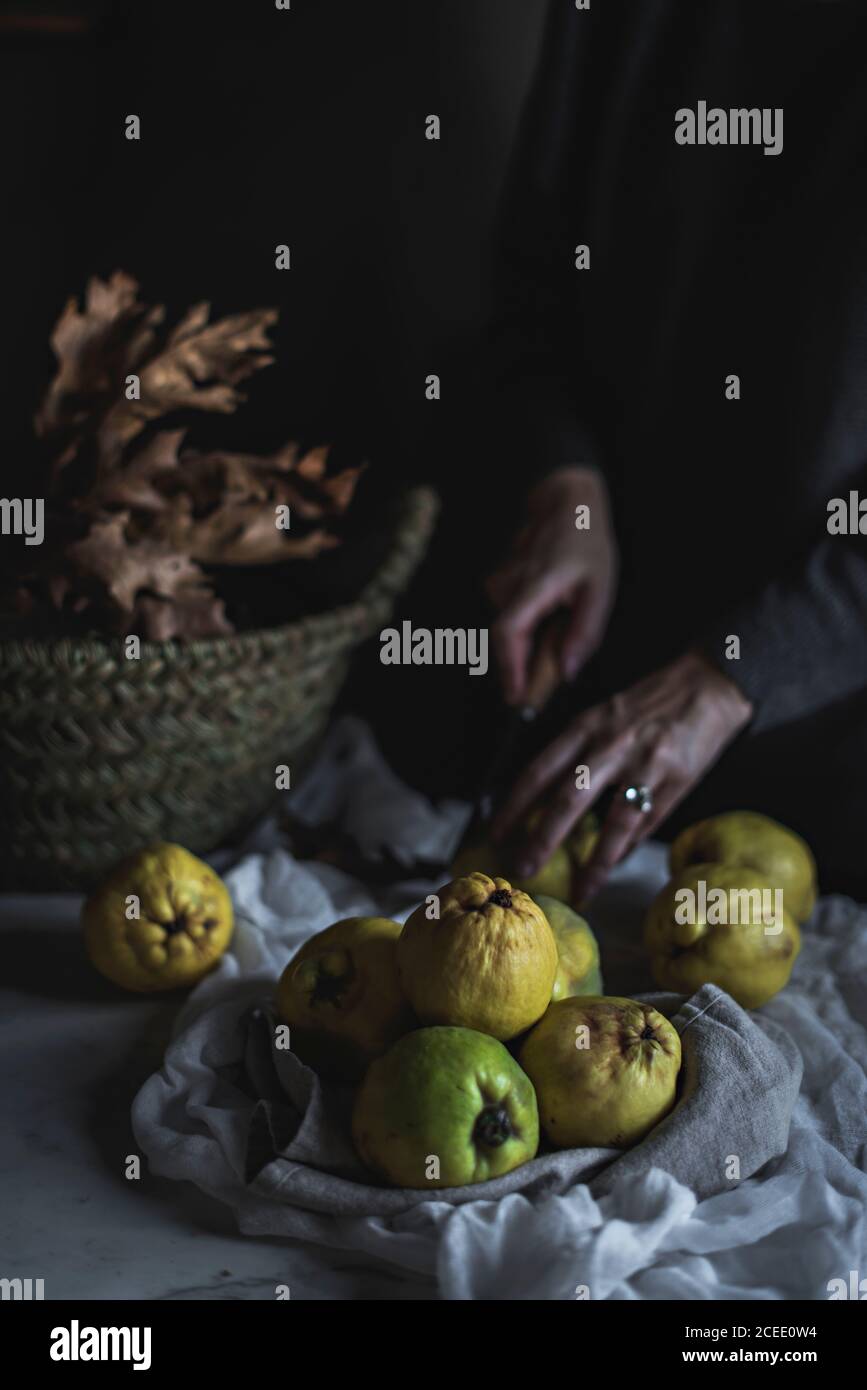 Crop Woman peeling frutta esotica sul cesto Foto Stock
