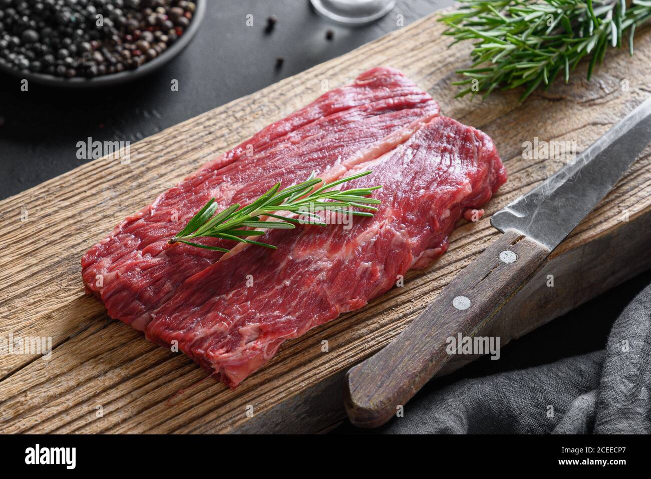 Bistecca di ribeye in marmo crudo con sprig di rosmarino su tagliere woden. Primo piano. Foto Stock