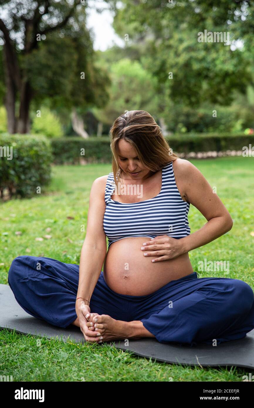 Gravidanza attraente Donna meditare sul tappeto nel parco Foto Stock