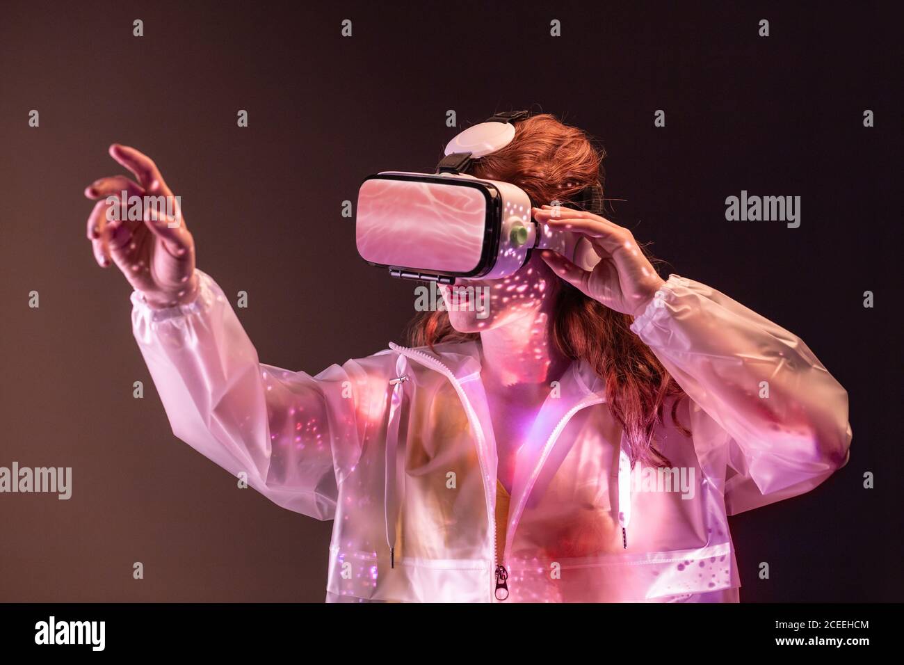 Giovane donna irriconoscibile che tocca l'aria e indossa cuffie per realtà virtuale in studio Foto Stock