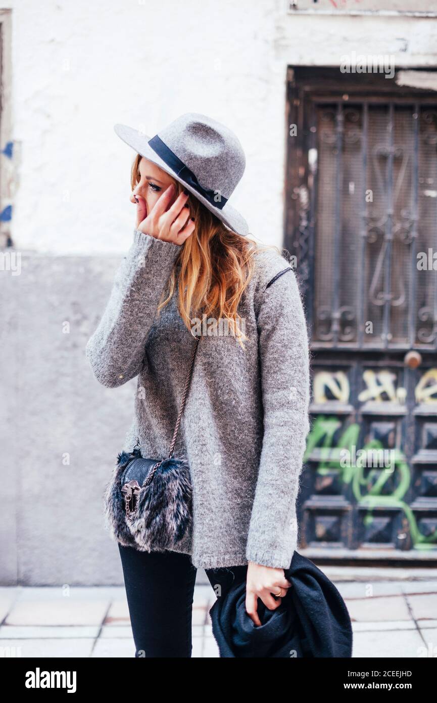 Ritratto di giovane donna bionda che indossa cappello e sciarpa nelle strade di madrid Foto Stock