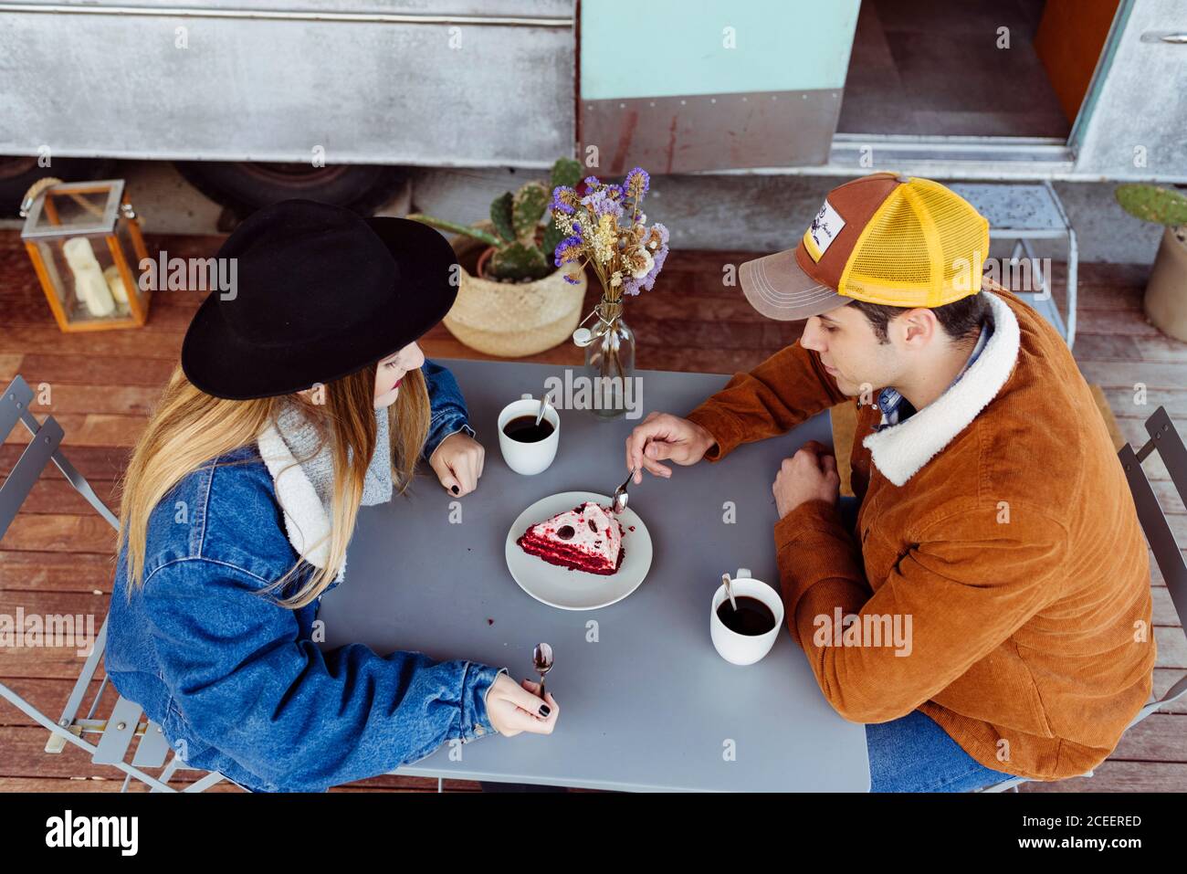 Giovane uomo e donna gustando una deliziosa torta mentre si siede al tavolo vicino a un pulmino grungy Foto Stock