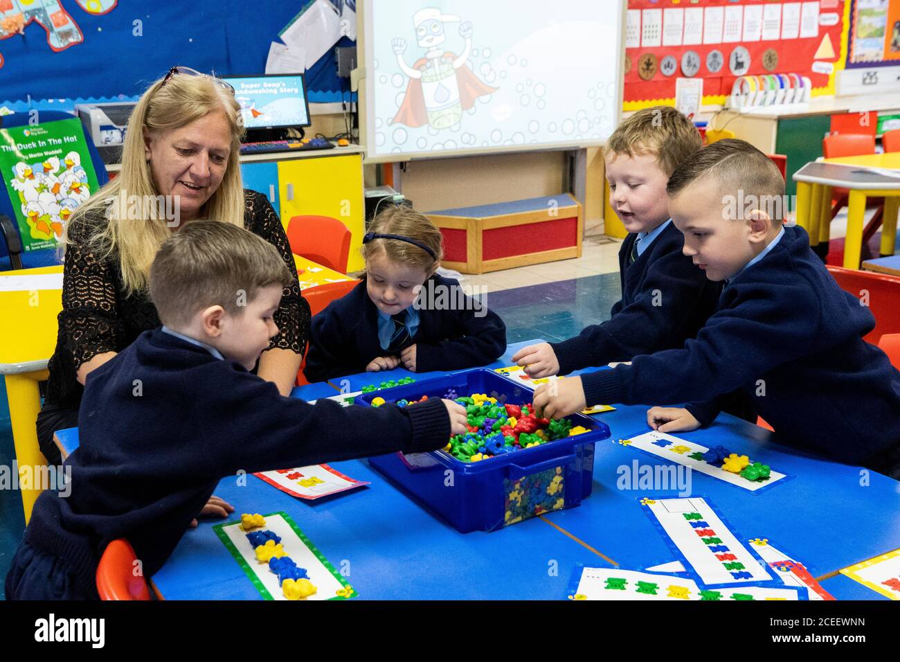 L'insegnante Joanne Conlon con alcuni dei suoi allievi di classe il primo giorno in P1 alla St John the Baptist Primary School a Belfast ovest, poiché quasi tutte le scuole si sono riaperte e oltre 300,000 studenti sono tornati a scuola in Irlanda del Nord per la prima volta da metà marzo. Foto Stock