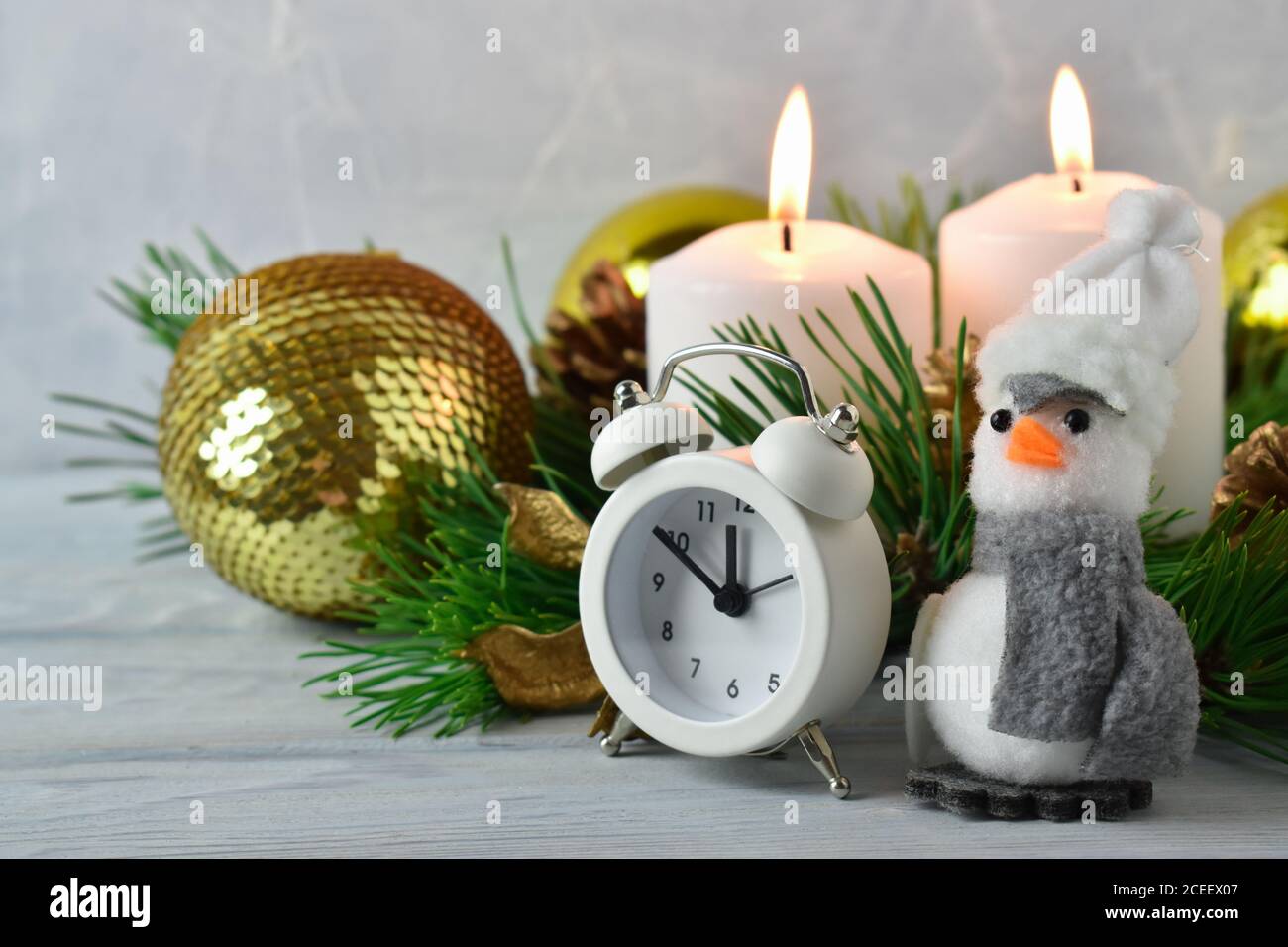 Composizione di Natale, rami verdi, palle dorate di Natale, sveglia e pinguino. Foto Stock