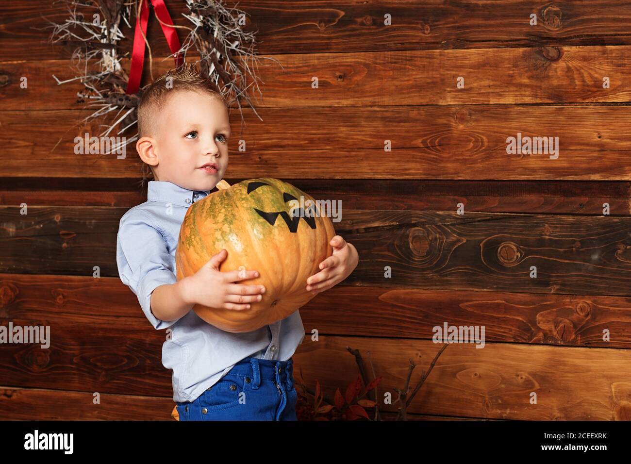 Festa di Halloween con bambino che tiene la zucca dipinta. Cute Little Boy divertirsi nelle decorazioni di Halloween Foto Stock