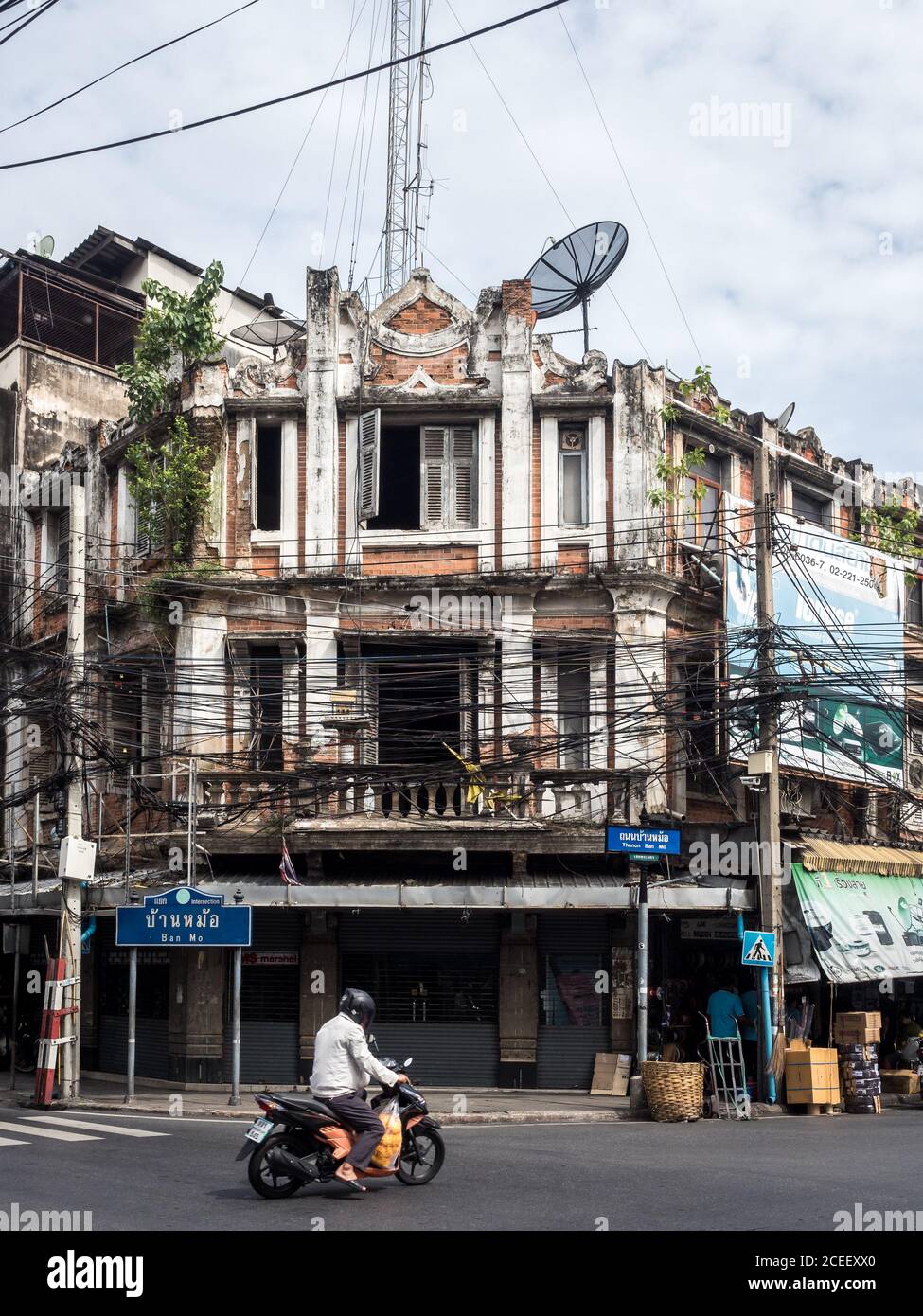 Bangkok, Thailandia, Sud-est asiatico - una persona che corre in moto di fronte al vecchio edificio coperto di piante verdi. Foto Stock