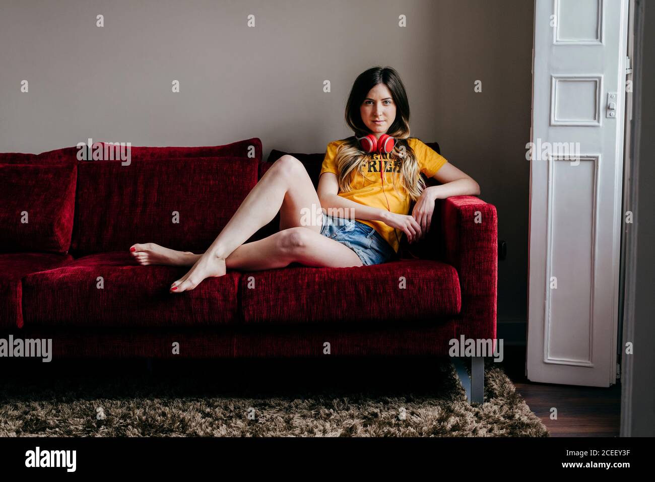 Donna con cuffie sul divano Foto Stock