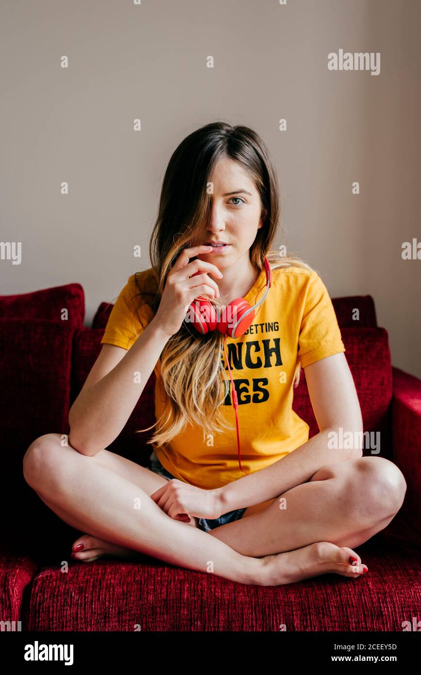 Donna con cuffie sul divano Foto Stock