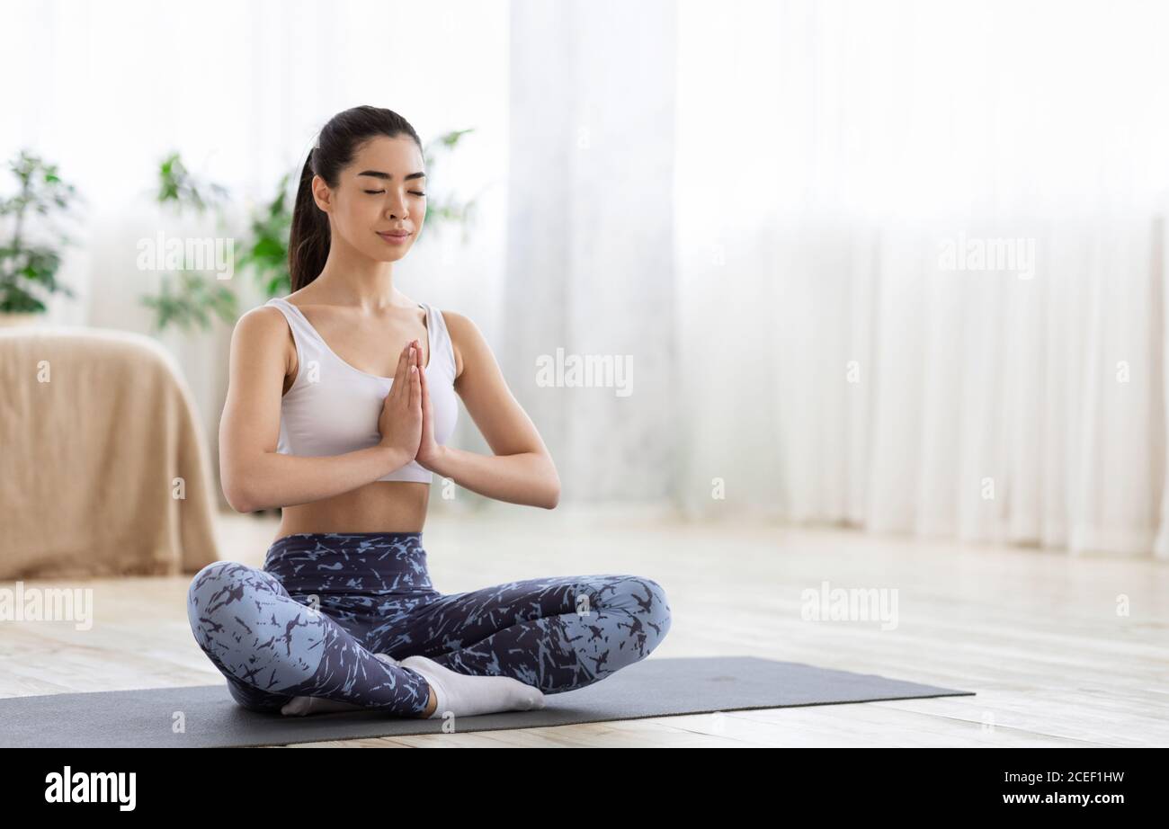 Meditazione mattutina. Ragazza coreana sportiva pratica esercizi di yoga a casa Foto Stock