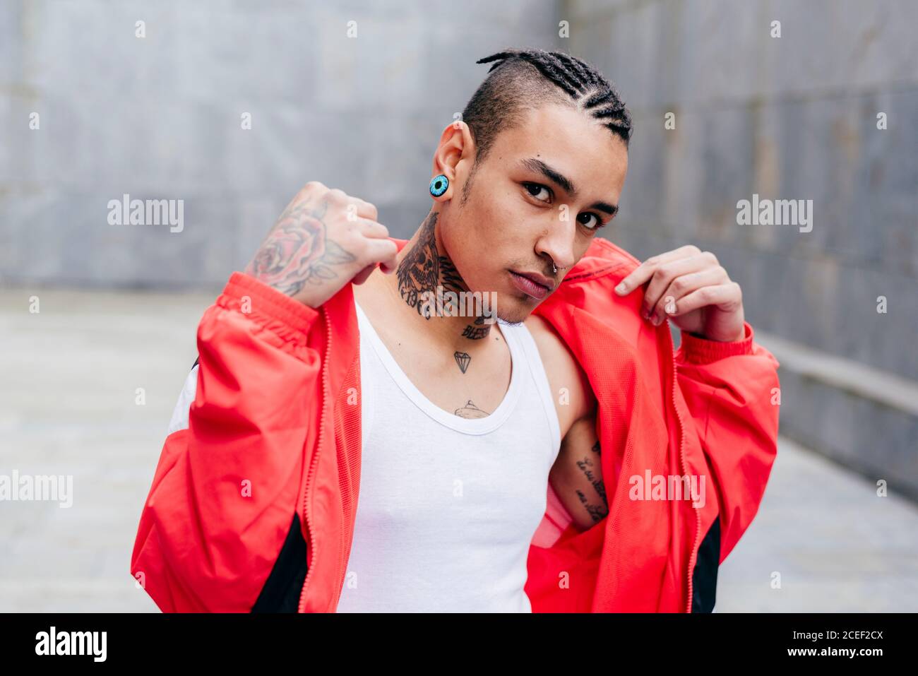 Uomo trendy con tatuaggi sul collo e sulle mani Foto Stock
