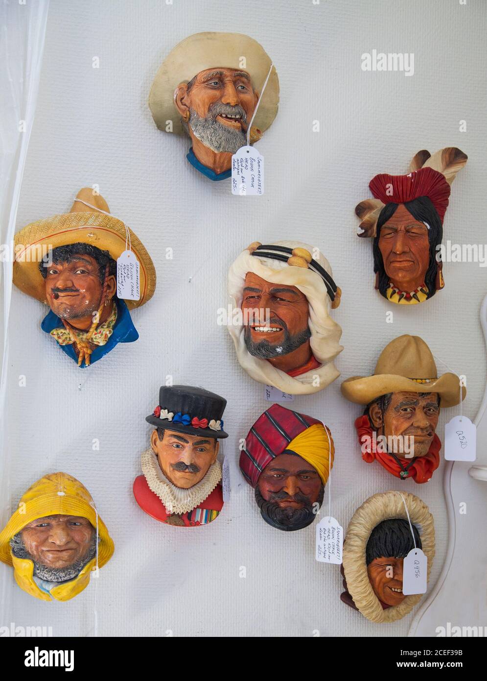 RACCOGLIE gli articoli in ceramica che rappresentano facce diverse con i headdresses su parete Foto Stock