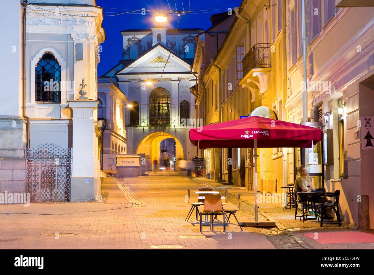 Vista notturna della Via Aussos Vartu illuminata nella Città Vecchia di Vilnius, Lituania. La porta dell'alba (porta Sharp) con l'icona della Madonna nella ba Foto Stock
