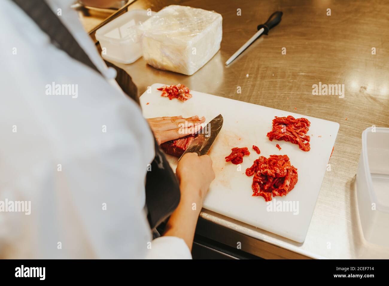 Un cuoco professionista irriconoscibile che affina la carne in una cucina del ristorante. Foto Stock