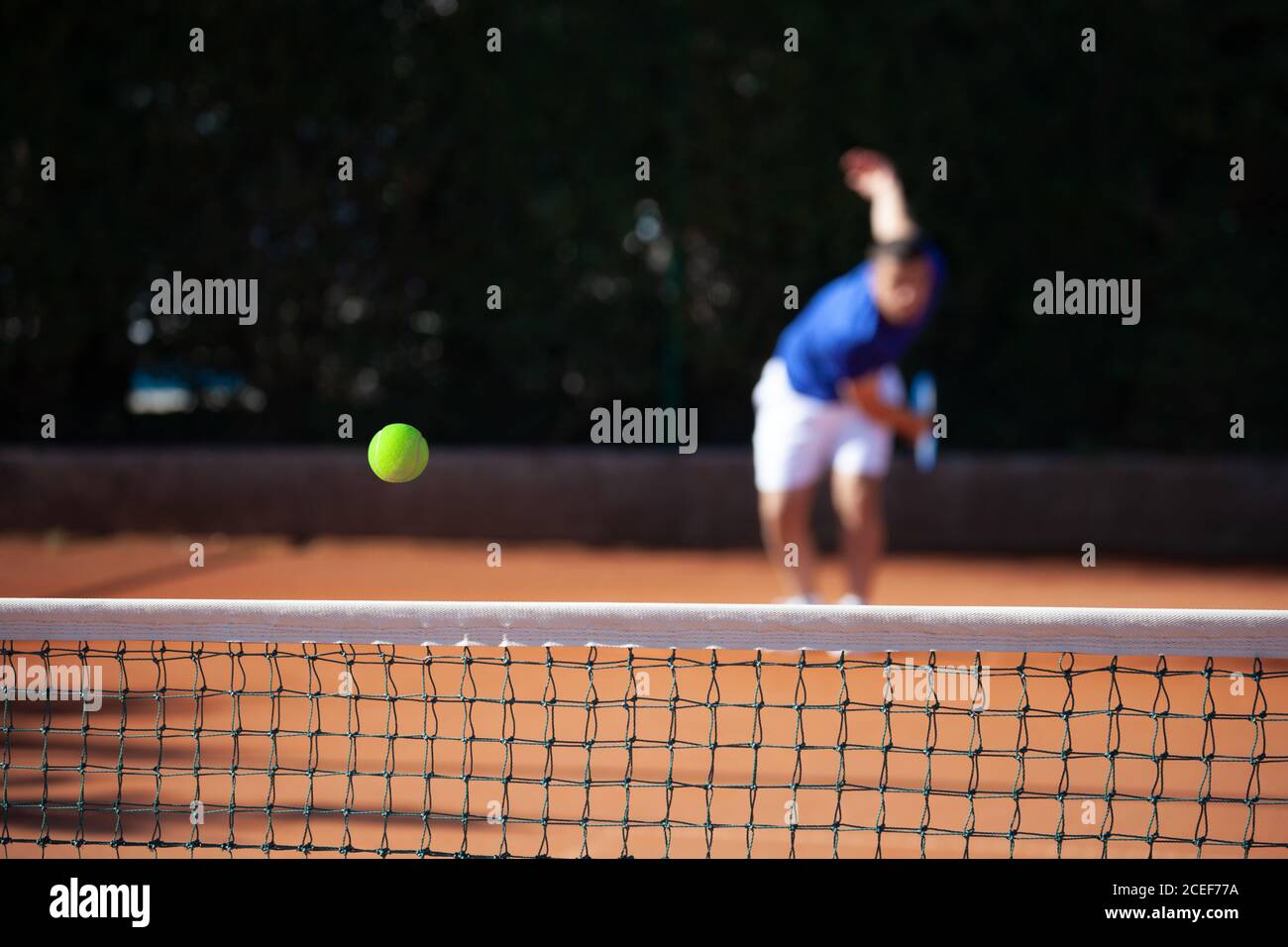 Palla da tennis appena sopra la rete dopo potente primo servire di un giocatore Foto Stock