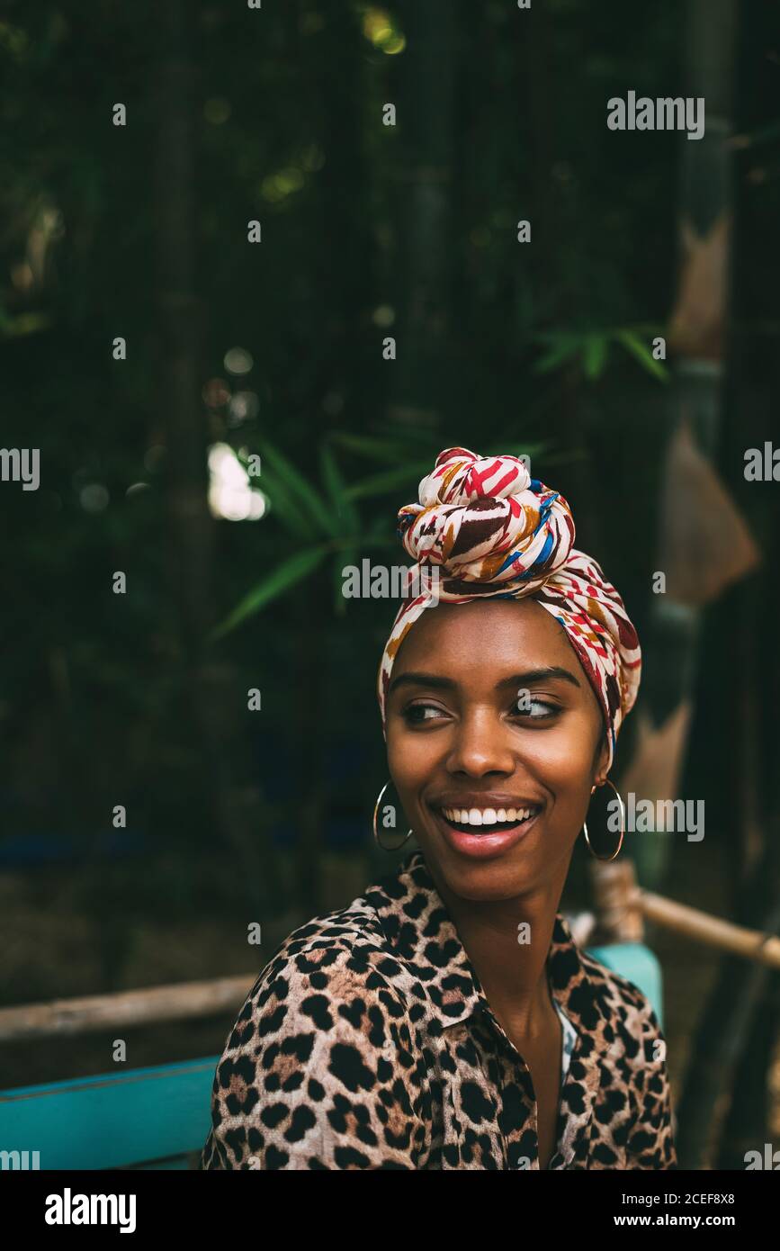 Donna con capo avvolgente seduta in un bel giardino Foto Stock