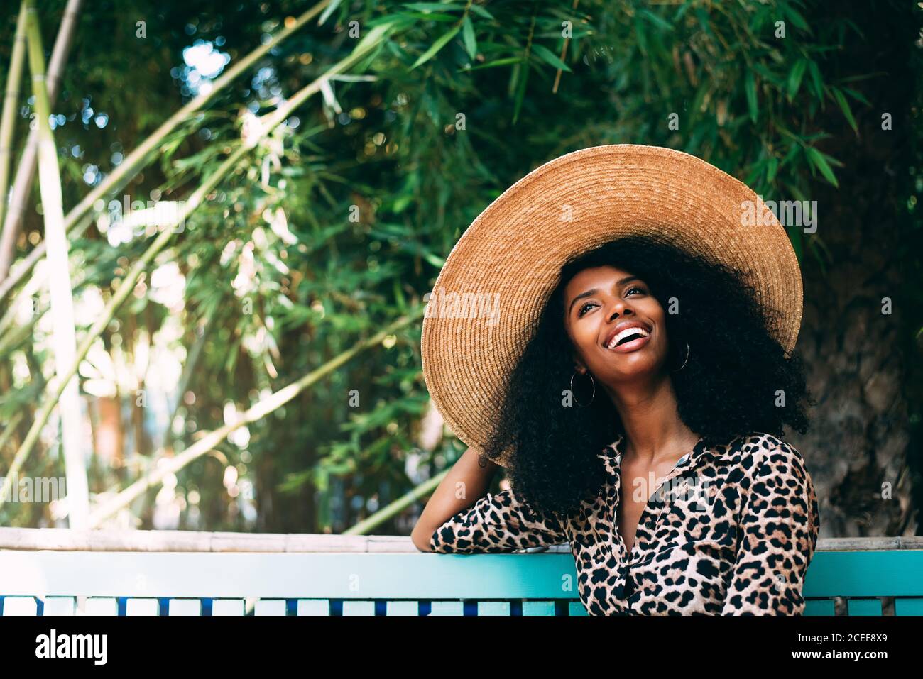 Donna con cappello di paglia seduta in un bel giardino Foto Stock
