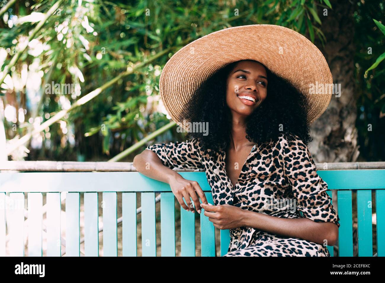 Donna con cappello di paglia seduta in un bel giardino Foto Stock