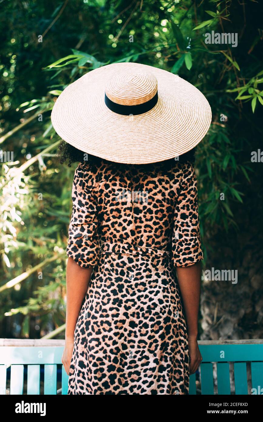 Vista posteriore di una donna con un cappello di paglia in un bel giardino Foto Stock